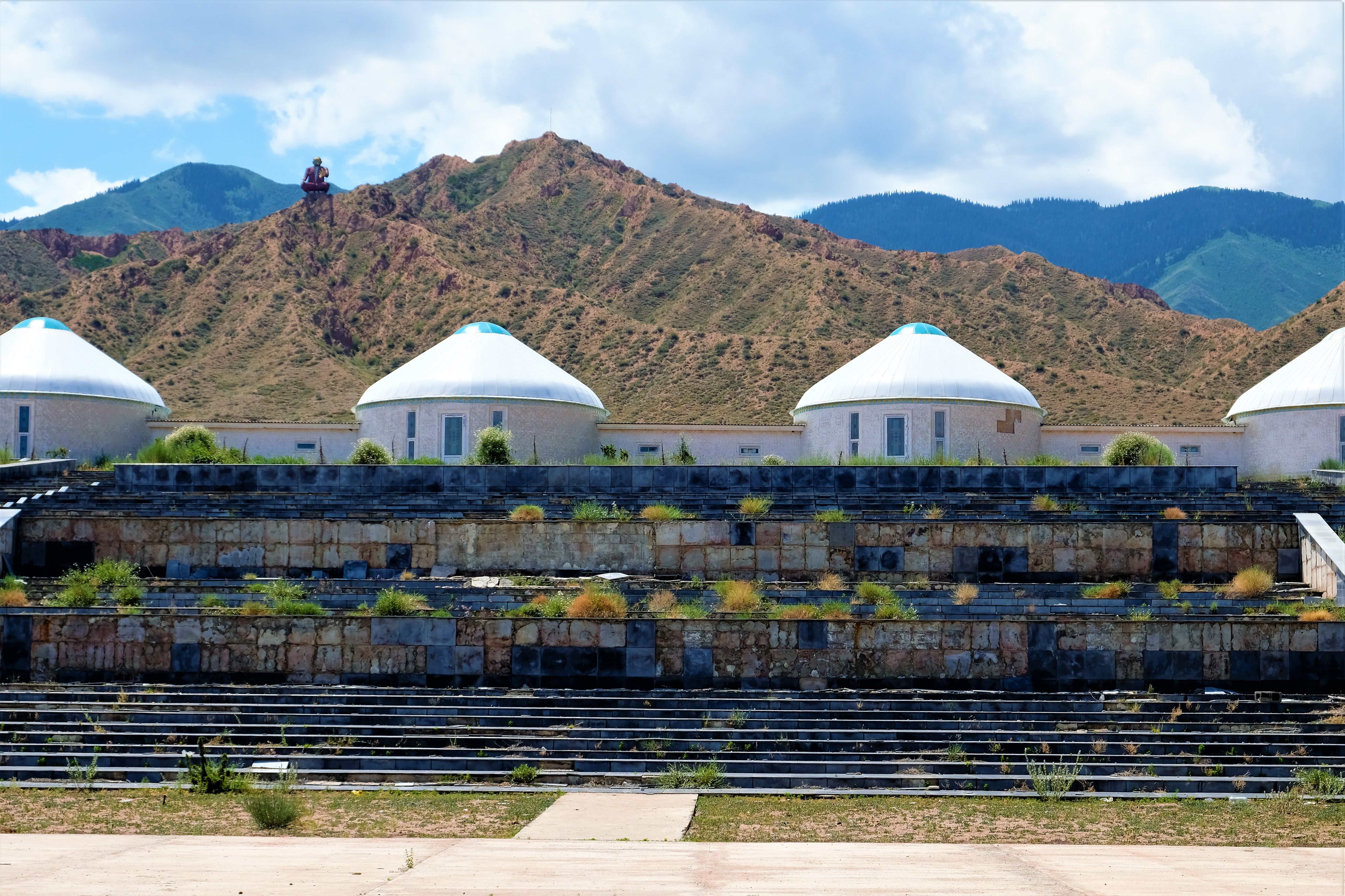Yurts of Aalam Ordo with a buddah statue on a mountain in the background